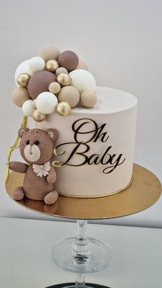 a teddy bear sitting on top of a white cake covered in gold and white decorations