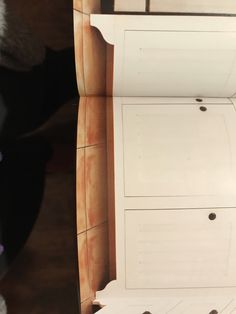 a cat sitting on top of a white shelf next to a wall with holes in it