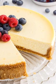 a cheesecake with berries on top is cut in half and ready to be eaten