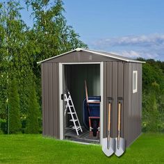 a garden shed with two shovels and gardening tools in it, sitting on the grass