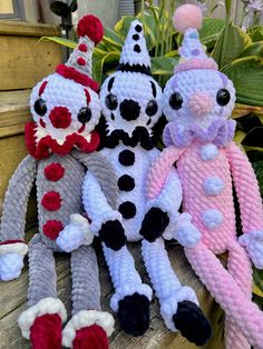 three knitted stuffed animals sitting on top of a wooden bench in front of plants