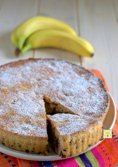 a cake on a plate with two bananas in the background and a napkin underneath it