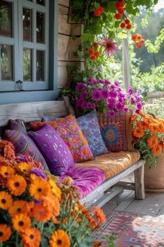 an outdoor porch with flowers and pillows on the bench, as well as potted plants