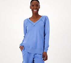 a woman in blue is smiling while wearing sweatpants and a sweatshirt with an open v - neck