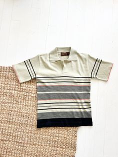 Vintage 1960s Knit striped polo Sundowner by Erika Strasberg gorgeous tan khaki coloring with black and red stripes excellent condition/some pilling 100 % acrylic made in Hong Kong listed as a size large Measurements Length: 25" Chest: 19" Sleeves: 9.5" Shoulder to Shoulder: 17.5" Measurements are taken flat Measurements: please allow a little extra room for comfortable fit and ease of movement These measurements are a guide. When in doubt, measure a garment that is comfortable and compare the m Retro Summer Polo Shirt, Vintage Fitted Polo Shirt, Retro Short Sleeve Polo Shirt With Striped Collar, Retro Short Sleeve Polo Shirt For Spring, Retro Cotton Polo Shirt For Spring, Retro Polo Collar Top With Striped Detail, Retro Striped Polo Shirt With Polo Collar, Retro Polo Collar Top With Stripes, Retro Striped Polo Shirt