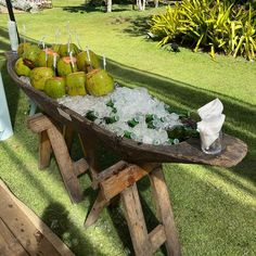 a wooden table topped with lots of bottles and glasses filled with ice sitting on top of grass