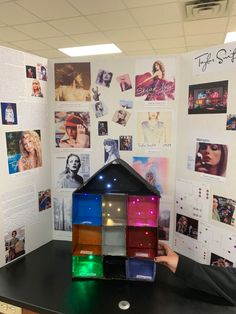 a person holding up a model of a house made out of legos on a desk