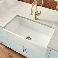 a white kitchen sink sitting under a faucet on top of a wooden counter