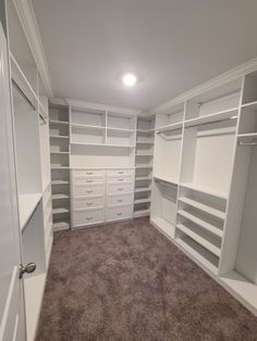 an empty walk in closet with lots of shelves and drawers on the wall, along with carpeted flooring