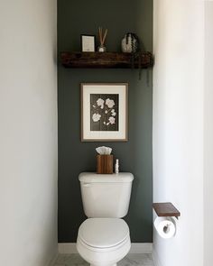 a white toilet sitting in a bathroom next to a shelf with pictures on top of it