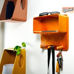 an orange shelf with some keys hanging from it's sides and other items on the wall