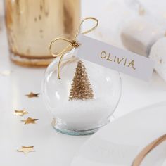 a glass ornament with a gold christmas tree on it and a name tag