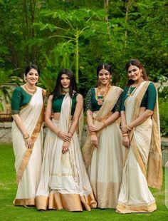 four women in white and green dresses posing for the camera with trees in the background