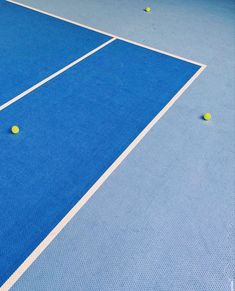 two tennis balls are on the blue court