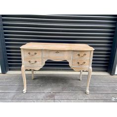 an old wooden desk with drawers in front of a garage door