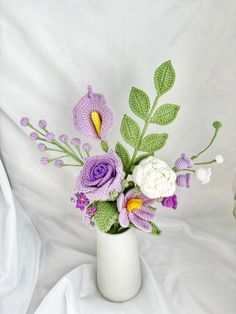 a white vase filled with flowers on top of a white cloth covered bedding area