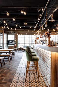 a bar with several stools and lights hanging from the ceiling in a restaurant setting