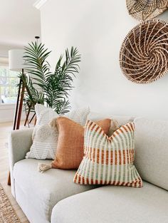 a white couch with pillows on it in front of a wall mounted wicker basket