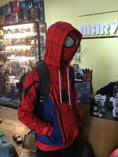 a person in a spider man costume standing at a counter with his hand up to the camera