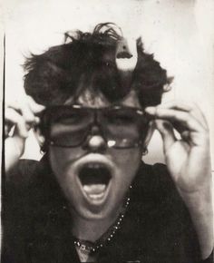 an old photo of a woman wearing glasses and pulling up her hair