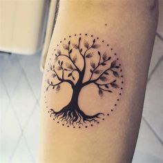 a black and white tree tattoo on the left leg with dots around it's branches