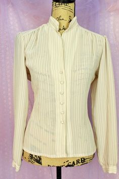 "Pre Loved Great Condition No Stains or Snags Vintage 70s Brand: RD. Beige/Gray Striped Sheer Button Up Blouse Long Sleeves 6 Front Button Closure Sheer Fabric Material: Polyester Career Blouse/Classy Style Size Approx. Small Medium Check the Measurements Below Measurements are taken Laying Flat Shoulder to Shoulder: 15 1/2\" Armpit to Armpit: 22\" Across Sleeves: 23\" Waist: 37\" Around Length: 23\" Shipping from 3-5 Days No Returns or Exchanges Thank you for Visiting..:)" Affordable Vintage Tops With Button Cuffs, Luxury Vintage Cream Blouse, Fitted Retro Cream Top, Retro Collared Blouse With Buttons, Retro Collared Button Blouse, Vintage Formal Shirt With Button Closure, Classic Blouse With Buttons For Vintage Fashion, Retro Button-up Fitted Blouse, Vintage Fashion Collared Blouse With Buttons