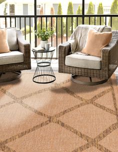 two chairs and a table on a porch with a rug in front of the chair