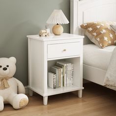 a white teddy bear sitting next to a night stand