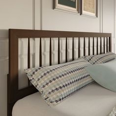 a bed with two pillows on top of it and pictures above the bedspread