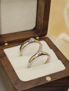 two gold wedding rings in a wooden box