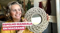 a woman holding up a round mirror in front of her face with the words espelho mandala em macrame on it