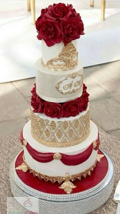 a three tiered wedding cake with red roses on the top and gold trimmings