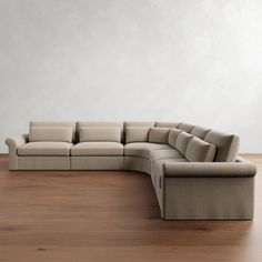 a large sectional couch sitting on top of a hard wood floor next to a white wall