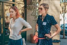 two women standing in front of a store with their hands on their hipss and looking at each other