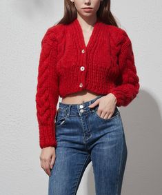 a woman in jeans and a red sweater is posing for the camera with her hands on her hips