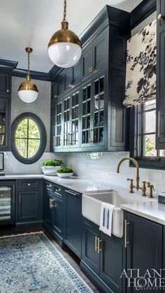 a large kitchen with blue cabinets and white counter tops, gold faucet lights above the sink