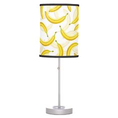 a lamp that has bananas on it with a black and white lampshade next to it