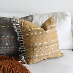 three pillows are sitting on a white couch with fringes and pom poms