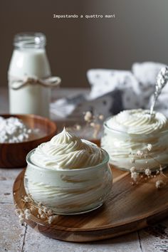 two bowls filled with whipped cream on top of a wooden plate