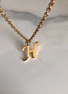 Letter H necklace, set on a stainless steel ,golden color chain. Chain length 19'  With addition cost there is an option to add a white freshwater pearl, as a charm, next to the letter. 6 mm, white round pearl Kindly choose your option. Beautiful spiritual gift. Please make sure you to pay attention to the size of the pendant. I have added pictures next to 25 cent coin, and measurement tape.  Need a different length just write it to me in the "message to the seller" box of the order form. **LIMI Initial Necklace H, H Necklace Initial, H Letter Necklace, Trendy Initial Necklace With Delicate Chain As A Gift, Trendy Initial Necklace With Delicate Chain For Gift, Minimalist Hypoallergenic Initial Pendant Necklace, Hypoallergenic Gold Initial Necklace Gift, Minimalist Hypoallergenic Initial Necklace, Elegant Gold Stainless Steel Initial Necklace