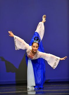 a woman in blue and white dancing on stage