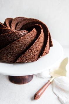 a chocolate bundt cake sitting on top of a white plate next to a spatula