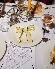 a table topped with white plates covered in cucumber slices and wine glasses next to each other