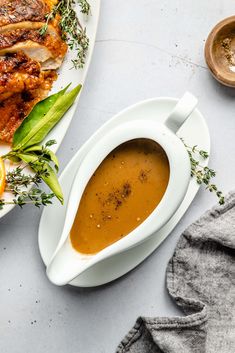 there is a plate with some meat and gravy next to it on the table