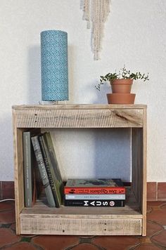 a book shelf with books and a vase on top, sitting in front of a wall