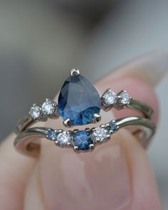 a woman's hand holding a blue and white diamond ring