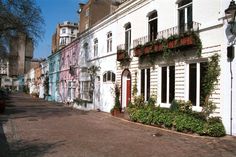 a street lined with tall white buildings and lots of plants growing on the side of it