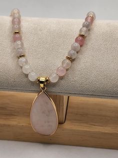 This stunning Rose Quartz necklace. The piece features a  polished teardrop pendant, elegantly framed in gold. The necklaces is strung with a delicate arrangement of soft-hued beads, blending shades of rose and translucent tones. Rose Quartz Necklace, Teardrop Pendant, Quartz Necklace, Blending, Halloween Shopping, Rose Quartz, Beauty Book, Beaded Necklace, Jewelry Necklaces