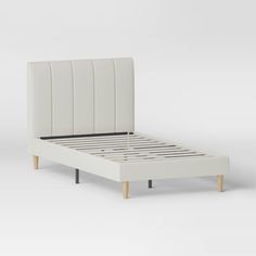 a white bed frame with wooden legs and headboard is shown in front of a gray background