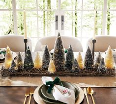 a dining room table set for christmas with place settings and napkins in front of it